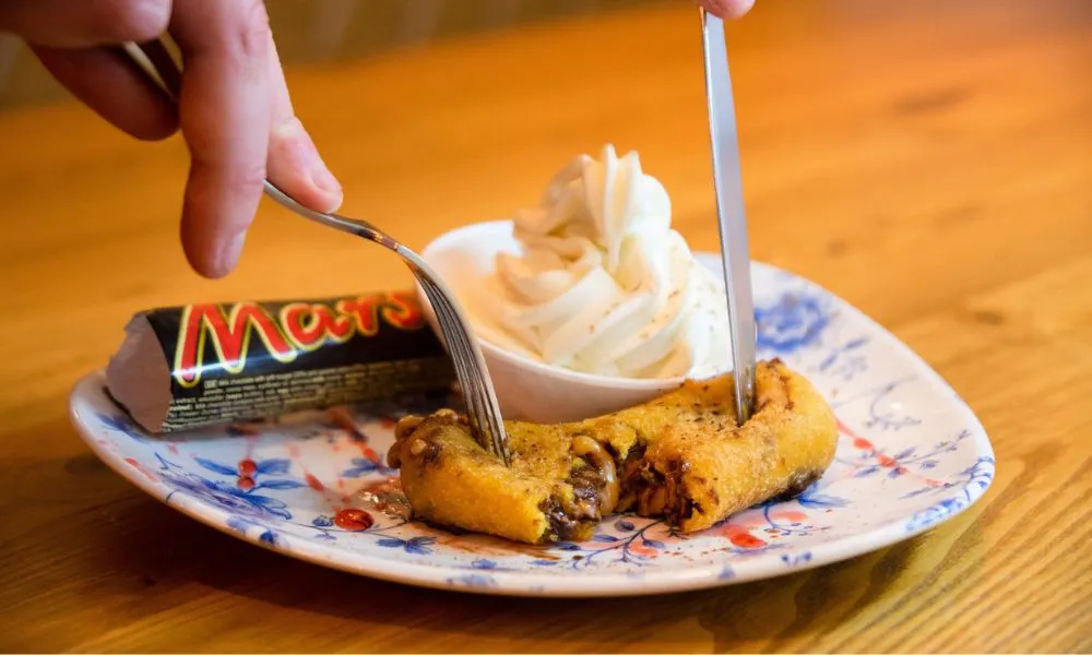 someone cutting into a deep fried mars bar