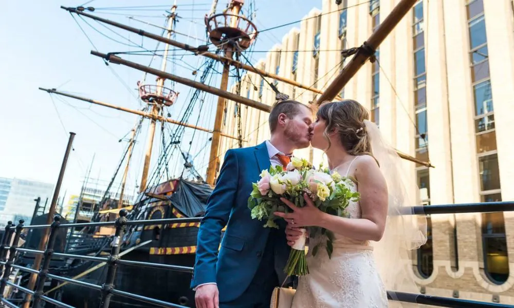 a couple on their wedding day kissing in front of a boat