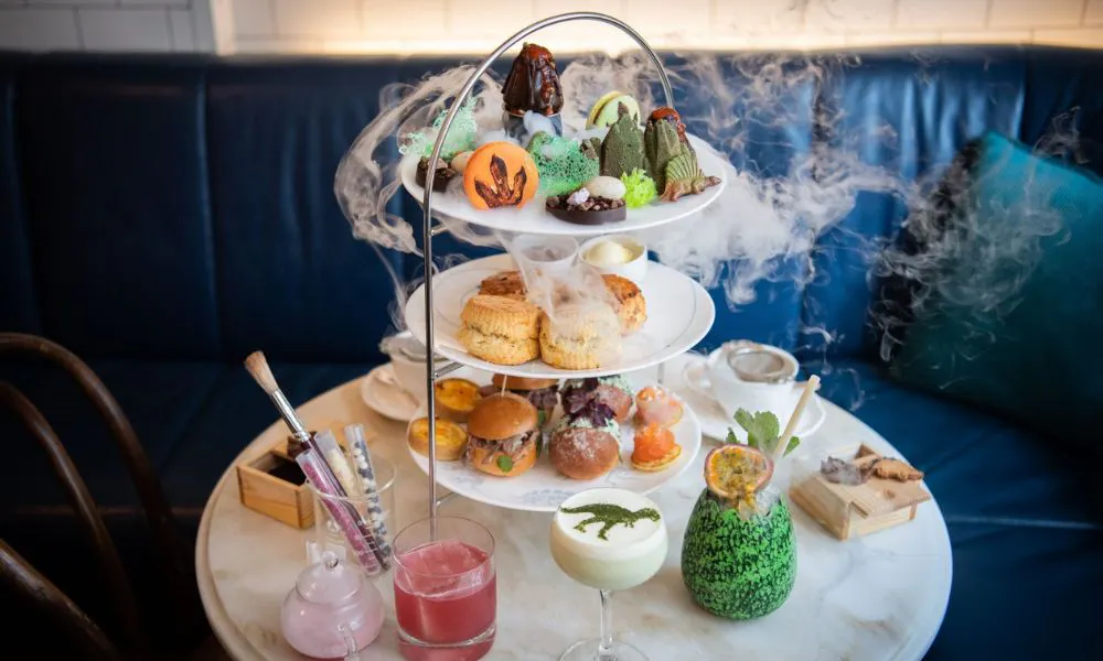 An afternoon tea stand with dry ice and dinosaur-themed treats