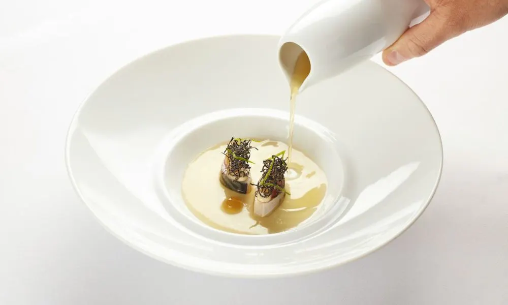 Hand pouring sauce over dish