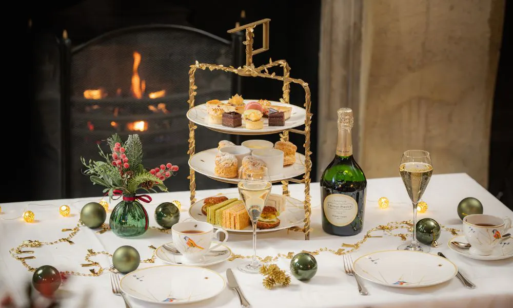 a three-tiered afternoon tea stand with tea cups and a bottle of fizz