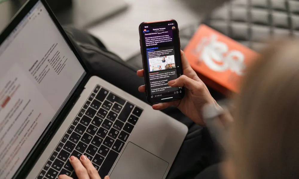 Hand holding phone and laptop