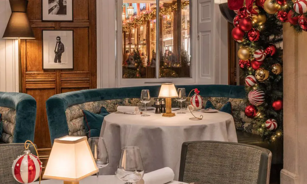 a white-clothed table set for dinner, surrounded by Christmas decor