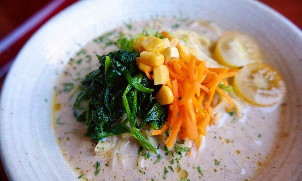 A bowl of Japanese soup topped with vegetables