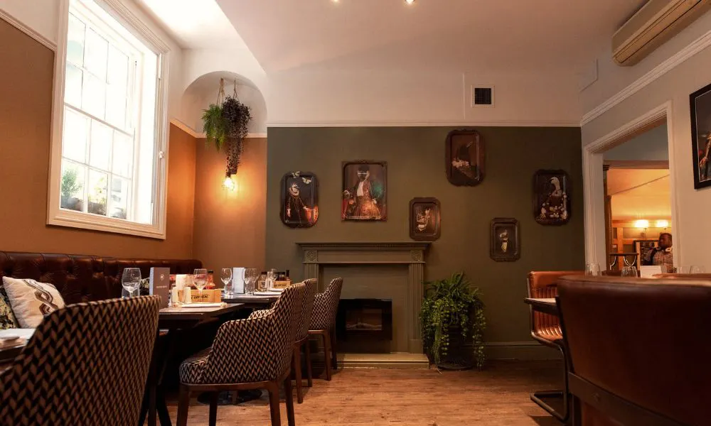 Dining room with paintings, leather seats, and plants