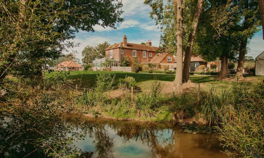 Red brick country house with a lawn, river, and trees