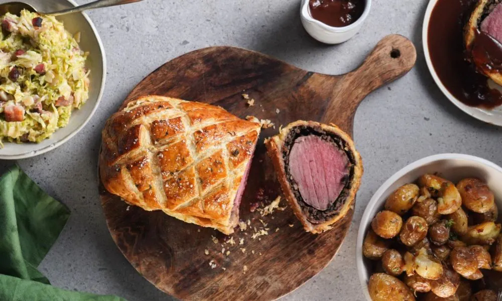 beef wellington cut open beside potatoes and cabbage