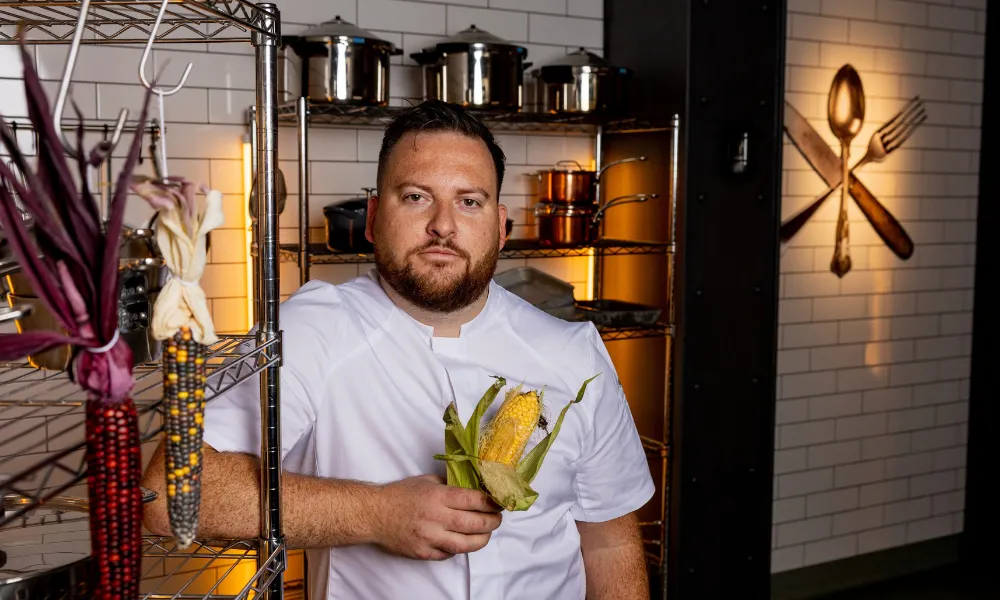 Cal Byerley standing holding an ear of corn
