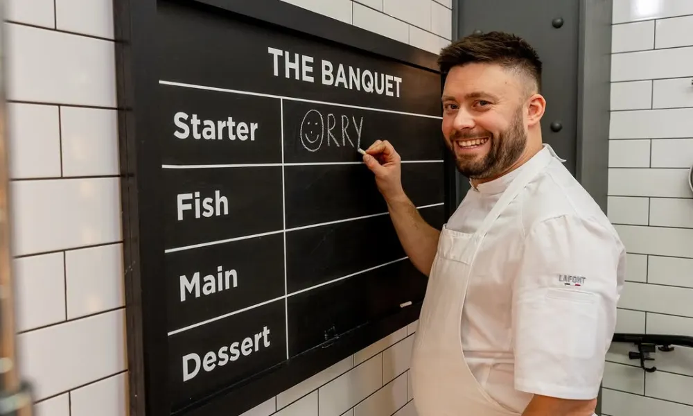 orry shand writing his name in the banquet menu