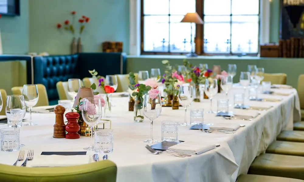 Long dining table with green chairs and flowers