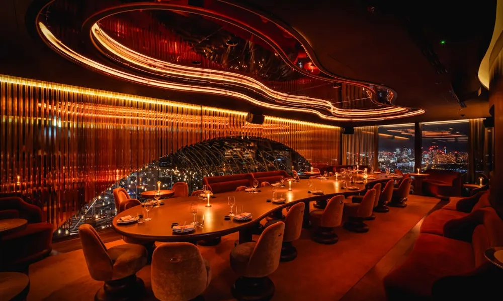 Long curving private dining table bathed in amber glow