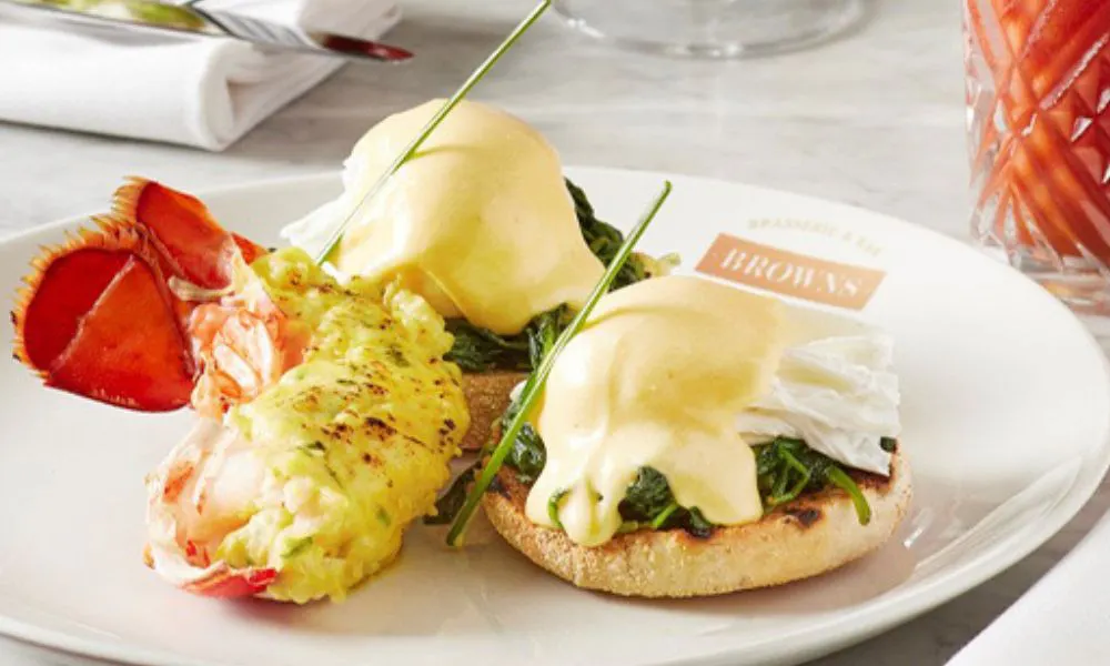 Two poached eggs with spinach and hollandaise sauce served with half a lobster's tail 