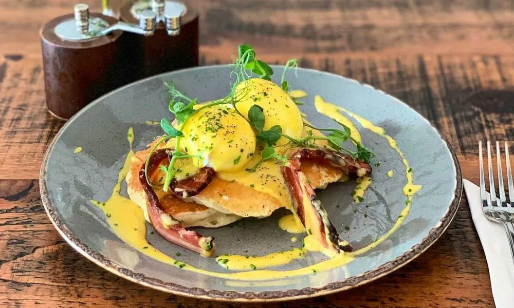 Eggs Benedict with yellow hollandaise sauce served on fluffy pancakes 