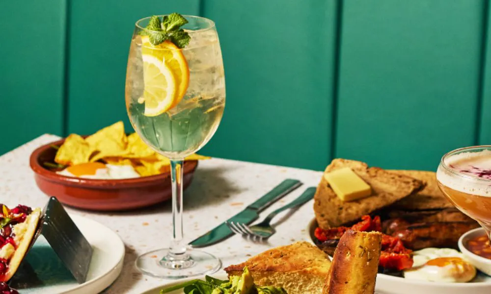 A cocktail served in a big wine glass with a selection of food including nachos and toast 