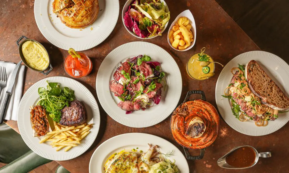 Table with plates of steak, pie and chips