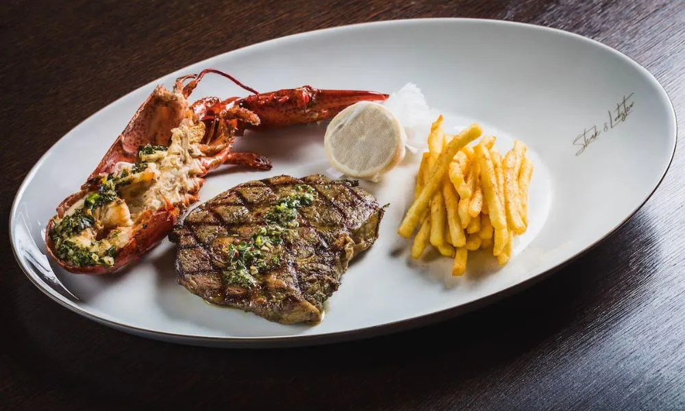 steak and lobster on a plate with fries
