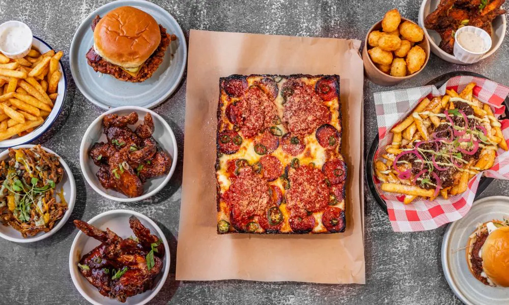 a selection of pizza, fries, burgers and chicken wings on a table